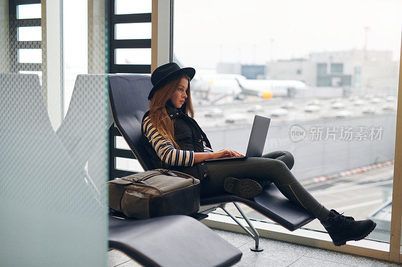 疲惫的年轻女子在机场用笔记本电脑