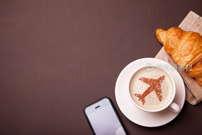 一杯泡着飞机的咖啡。飞机上的早餐咖啡和牛角面包。再来杯咖啡