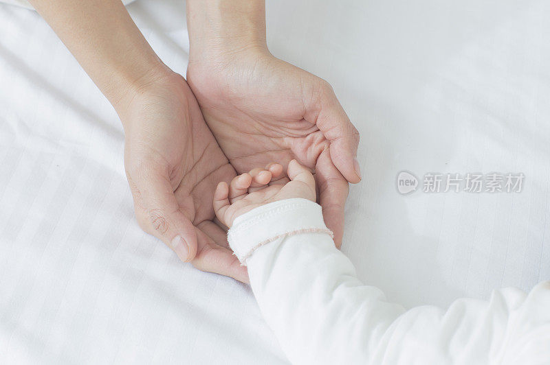 年轻妈妈捧着宝宝的手