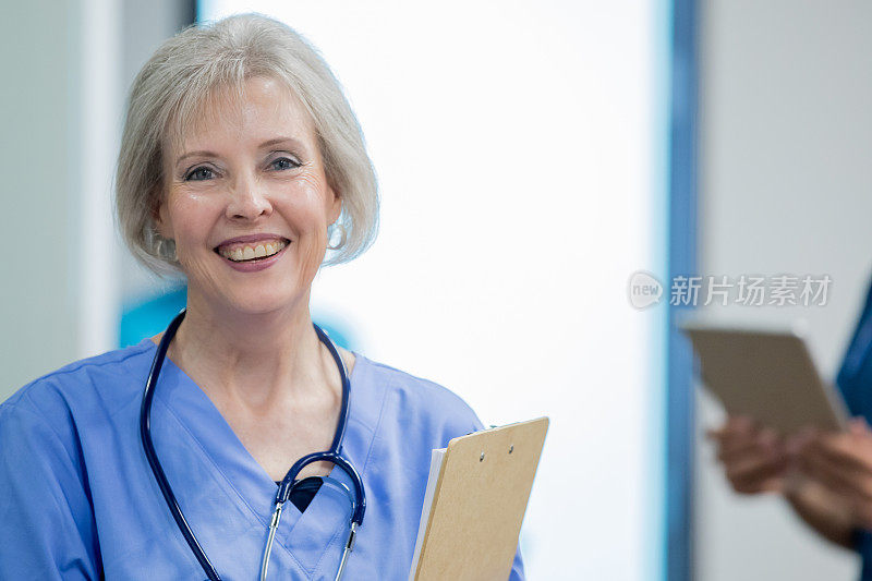 友好的高级成年女医生或护士在繁忙的急诊室工作在医院