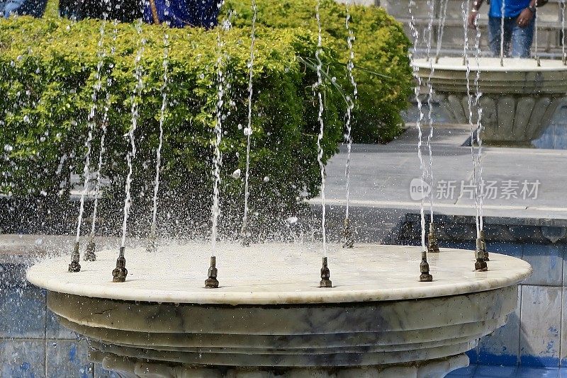 喷泉水景的图像在花园，大理石和黄铜洒水器的特写照片与修剪黄杨木篱笆(黄杨永久)的背景