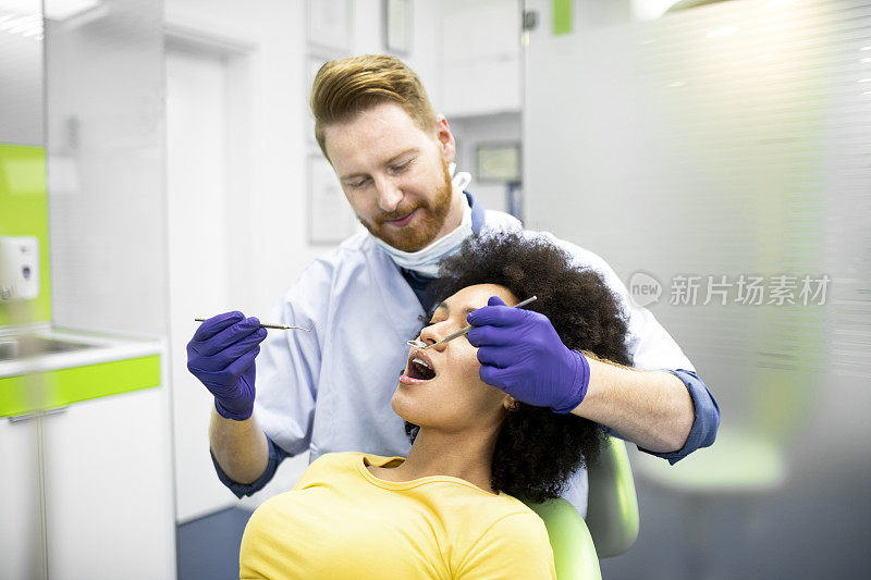 牙医使用挖掘机镰刀探针和口镜进行牙科检查