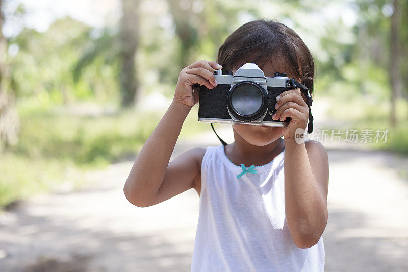小女孩拿着相机在花园里拍照