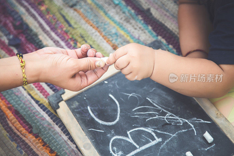 印第安母亲和女婴在黑板上用粉笔写字和画画