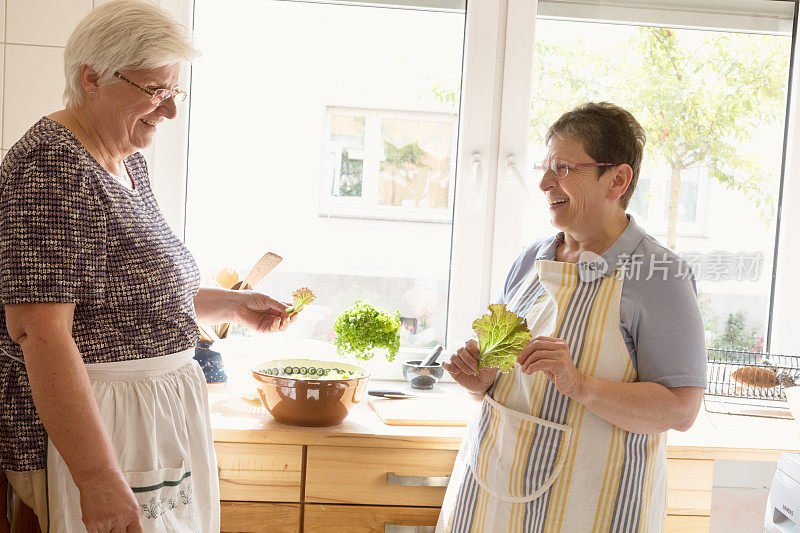 年长妇女在厨房里一起做饭，一起玩乐