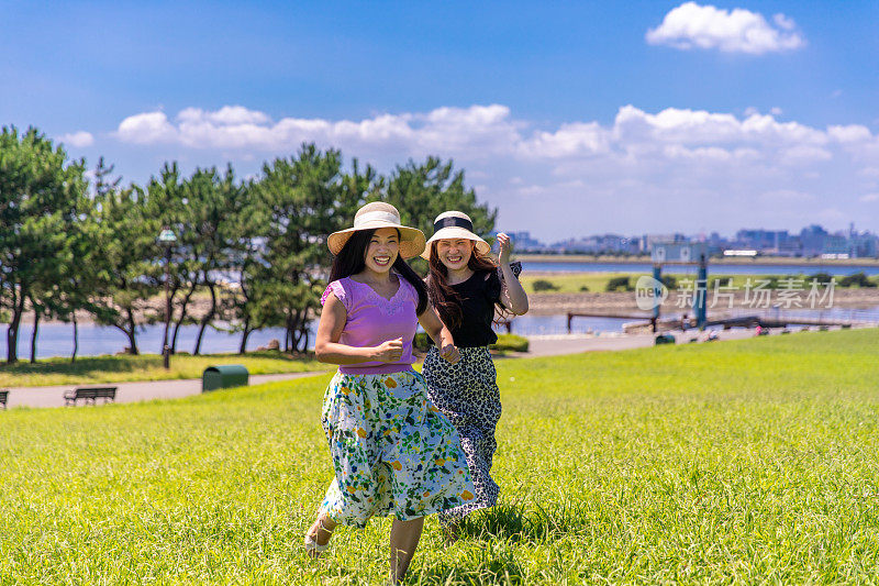 夏天，快乐的年轻女子在绿色的田野上奔跑