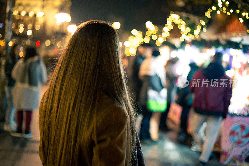 年轻女子晚上在圣诞市场