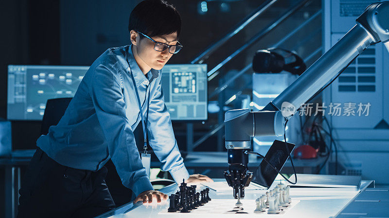 专业的日本开发工程师正在测试一个人工智能界面，用一个未来的机械臂下棋。他们在一个高科技现代研究实验室。