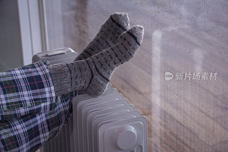 近距离图像的女人的脚散热器加热器在雨季的冬天。