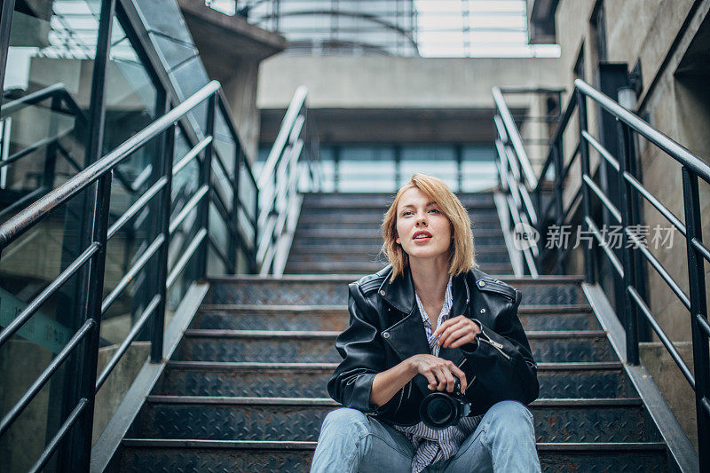 年轻时髦的女人坐在楼梯上拍照