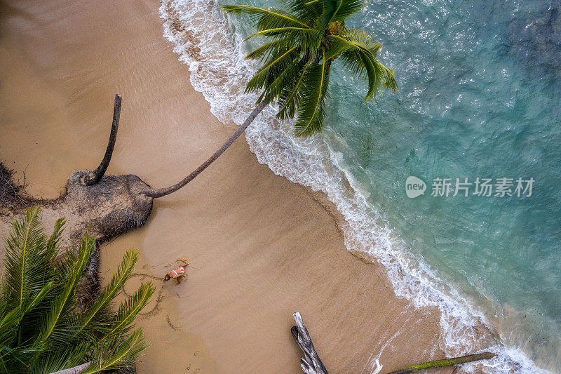 无人机的女人放松在金色的海滩附近的心画在沙子上