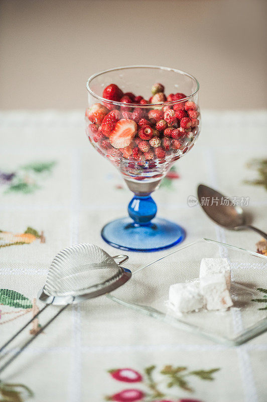 乡村餐桌上的玻璃碗里的新鲜野草莓