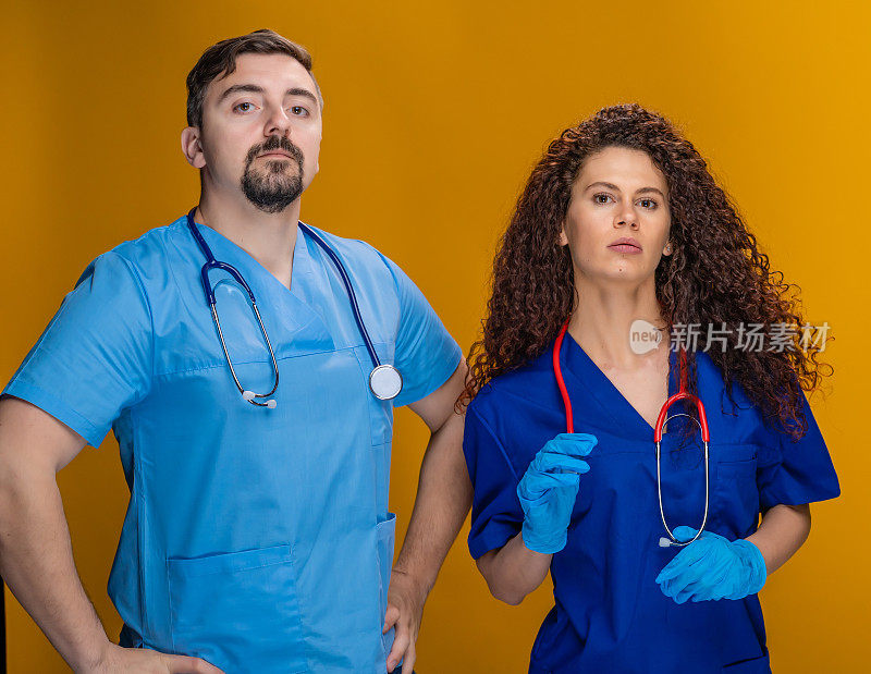 两名专业医生拿着听诊器看着摄像机，黄色背景