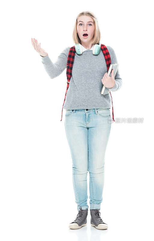 十几岁的女生穿着暖和的衣服，拿着课本，戴着耳机，站在白色背景前