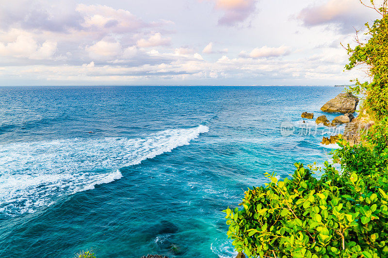 Uluwatu巴厘岛。蓝色的海洋和岩石山，覆盖着热带树木。