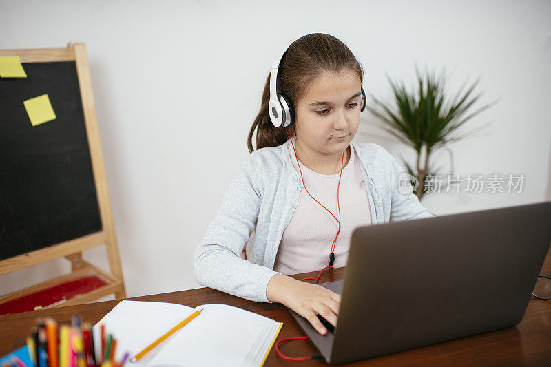 十几岁的女孩用笔记本电脑做作业
