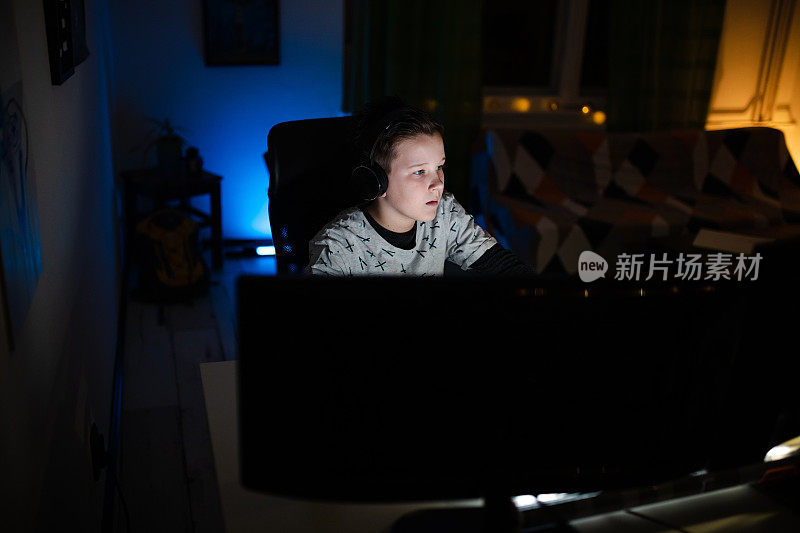 专注的玩家戴着耳机在晚上上网