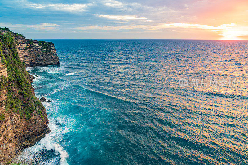 Uluwatu巴厘岛。蓝色的海洋和岩石山，覆盖着热带树木。