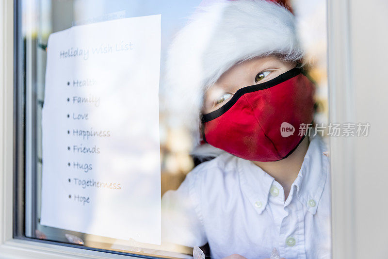 2019冠状病毒病大流行期间，一名小男孩在自家窗户上贴圣诞或节日礼物清单