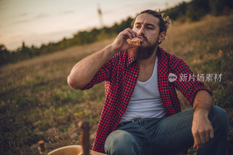 自然的守护者。一个在山上的男人，一个伐木工人，喝着自制的白兰地，吃着自制的食物，而在他身后是美丽的日落，休息辛苦的工作。