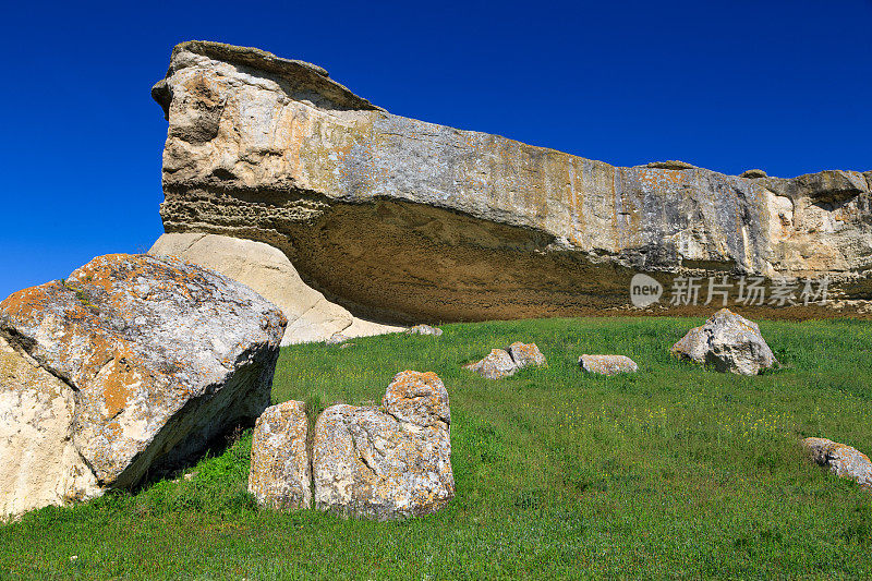 一块光滑巨大的岩石，从它的边缘可以看到广阔的视野。它是沙色的，几乎没有尖锐的棱角。