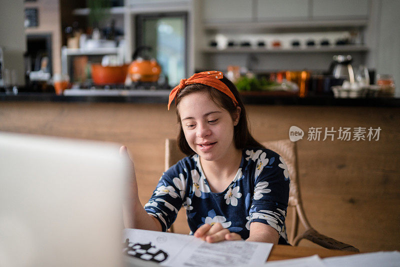 有特殊需要的女孩在家里用笔记本学习