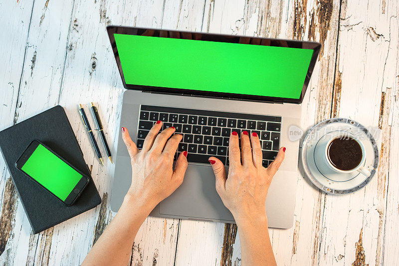 家庭办公室设置笔记本电脑绿屏智能手机绿屏记事本咖啡杯和笔都在白色桌子上横着拍照