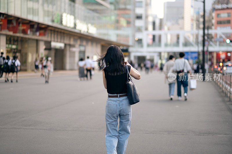 女人在街上行走的后视图