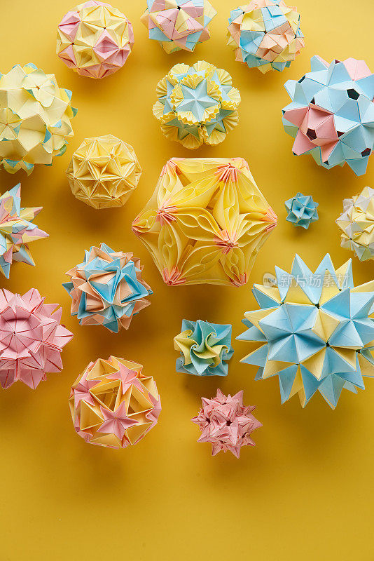 Set的multicolorÂ手工制作modularÂ折纸球或Kusudama孤立在黄色背景。视觉艺术，几何学，折纸艺术，纸工艺品。俯视图，特写，选择性聚焦，复制空间。