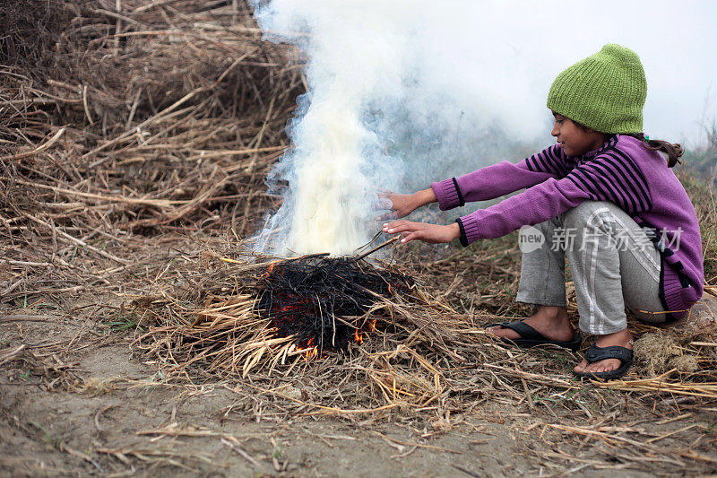 可怜的女孩在冬天用火取暖