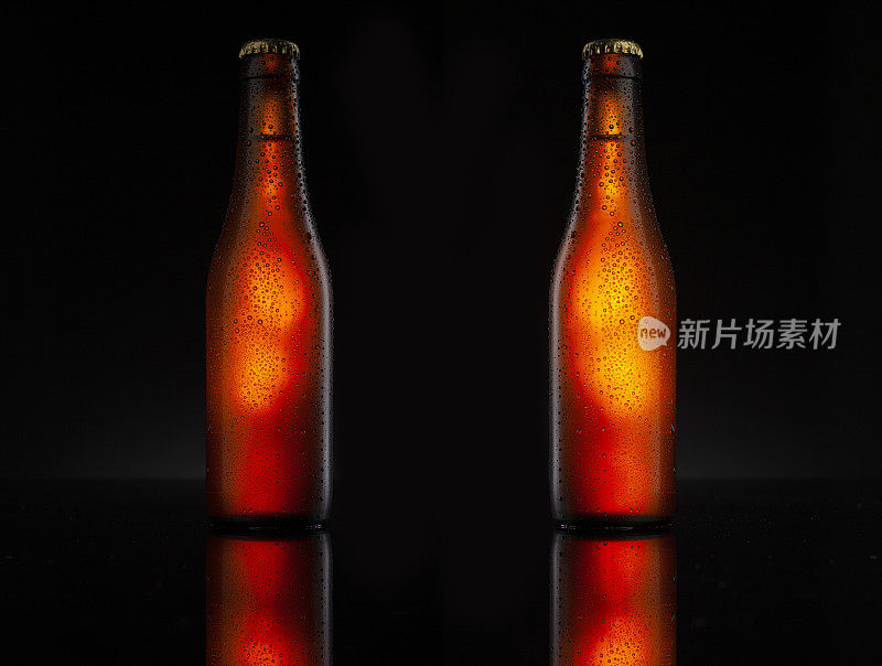 冰镇的两个棕色啤酒瓶上覆盖着冰和水珠-凝结。空白为饮料产品设计模型。站在黑色的桌子与黑色的背景。