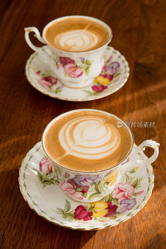 家庭咖啡师-在下午晚些时候的阳光下，用一对复古的骨瓷杯自制的纯白咖啡和脱脂牛奶