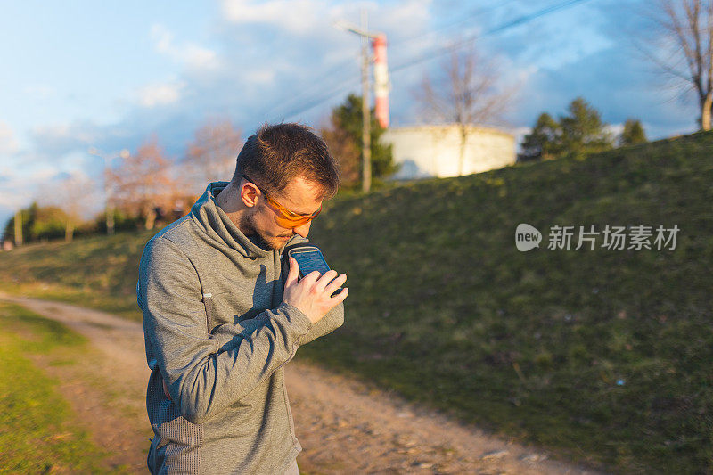 一名年轻男性跑步者在袖标手机壳内使用手机的特写镜头