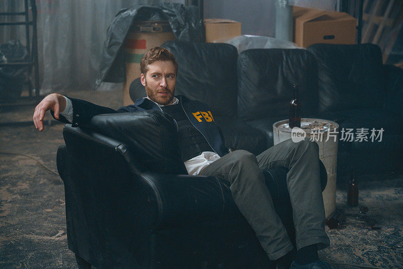 英俊的联邦调查局探员坐在犯罪现场的黑色扶手椅上