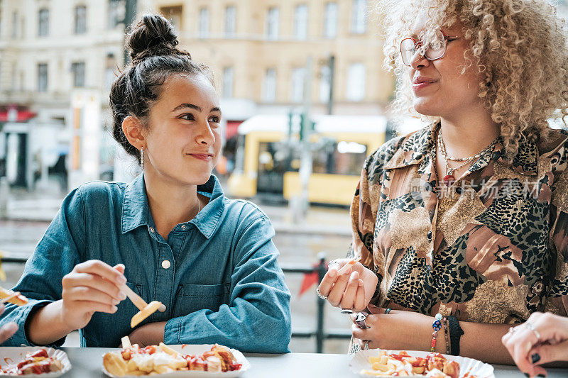 两个十几岁的女孩在柏林吃咖喱香肠和炸薯条