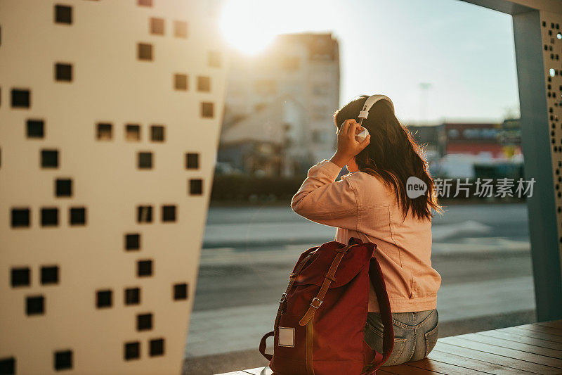 女人边听音乐边等车