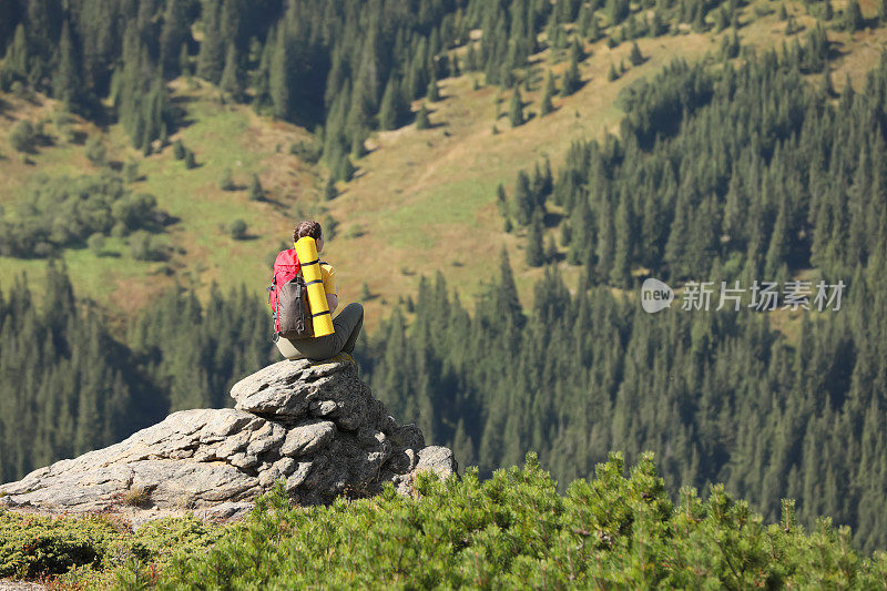 游客与背包享受山景，岩石山顶，背影