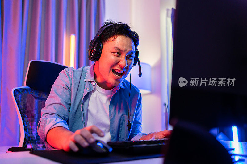 亚洲有魅力的电竞男性玩家在电脑上玩在线视频游戏。帅哥游戏玩家在家中玩网球赛的同时，享受着科技直播带来的快乐和兴奋