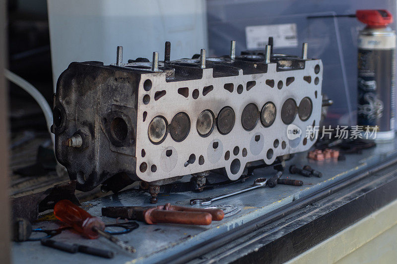 8V柴油发动机的旧气缸盖放在长凳或桌子上。可见燃烧的一面汽缸头，刚刚铣削或拉直。