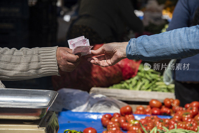 妇女在乡村市场买菜，付钱给杂货店