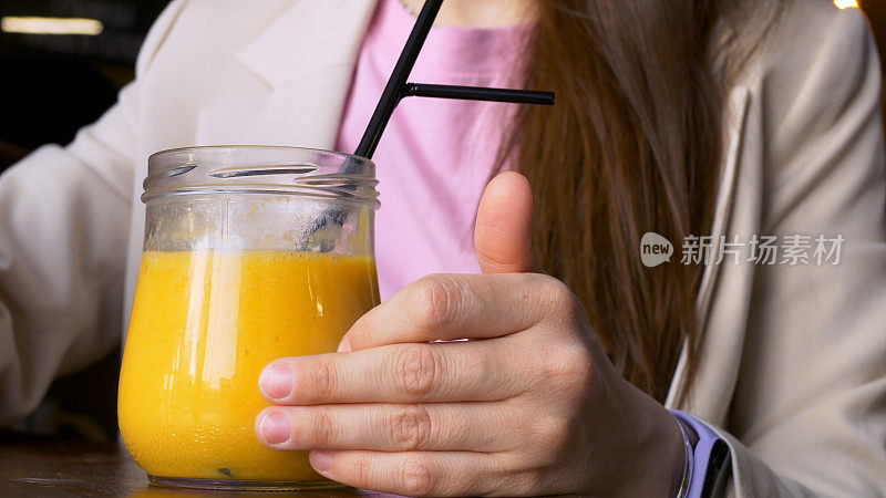 一个玻璃杯用勺子吃着黄色芒果冰沙的特写。从新鲜水果中摄取维生素，保持健康和心情。美味甜美的黄色芒果冰沙。