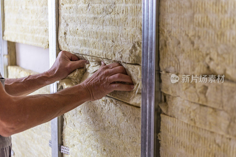 工人用矿物岩棉保温材料保温房间墙壁。