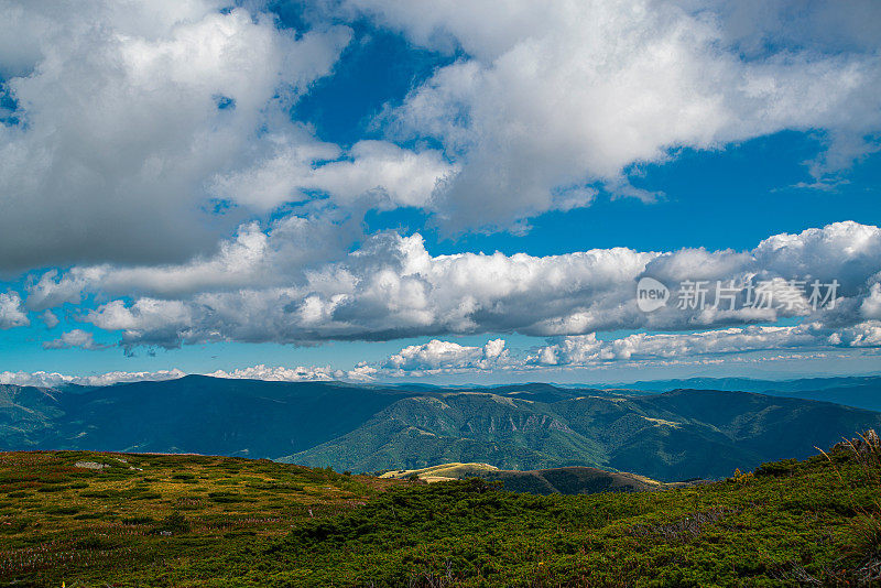 在一个阳光明媚的夏日里，有美丽的山峦和岩石景观。