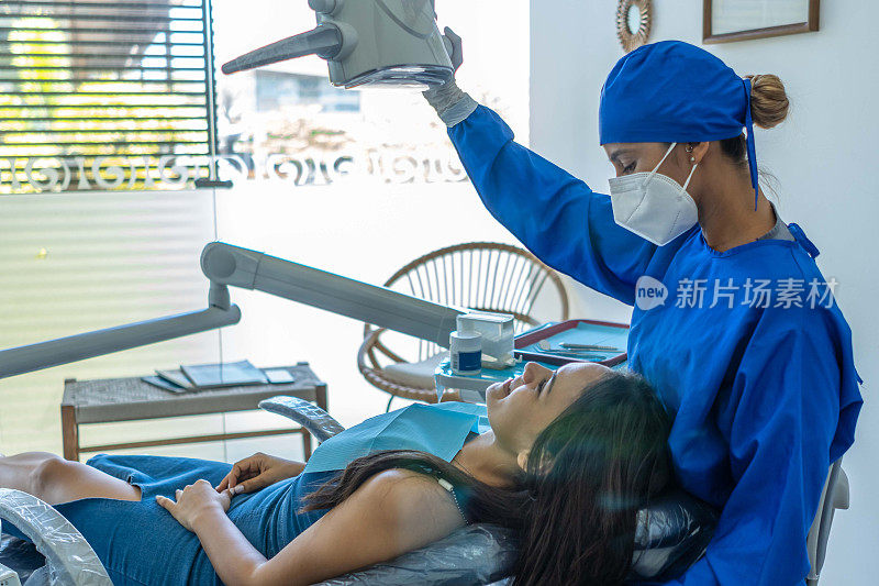 戴着口罩和手术服的牙医正在检查病人。