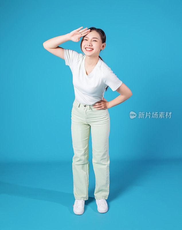 年轻亚洲女性站在蓝色背景上的全长照片