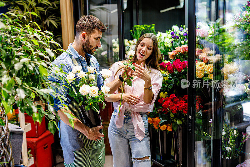 一位年轻女子在花店售货员的帮助下买花。