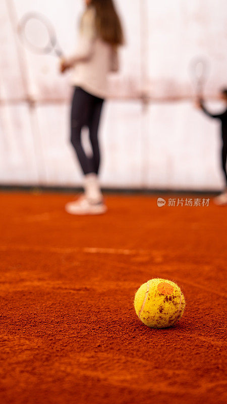 网球是在红土场上的焦点前景两个女子网球运动员是背景垂直网球仍然