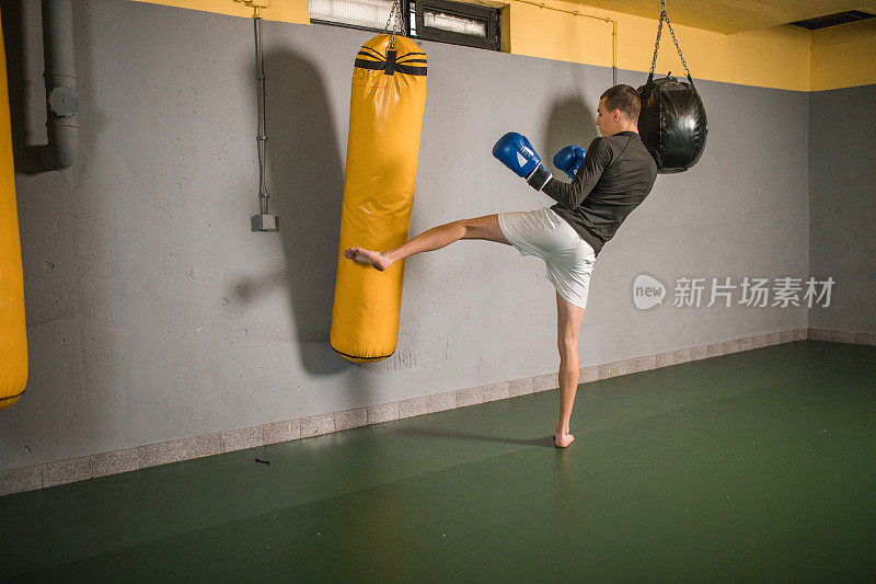 有动力的自由搏击运动员在健身房击打沙袋，锻炼肌肉