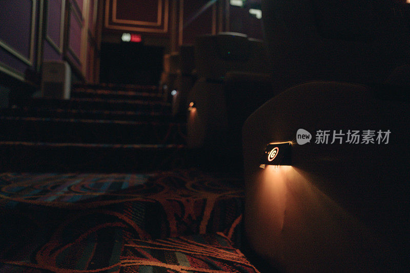 空荡荡的电影院的楼梯和过道。漆黑的电影院，只有亮的标志和红色的阶梯灯。