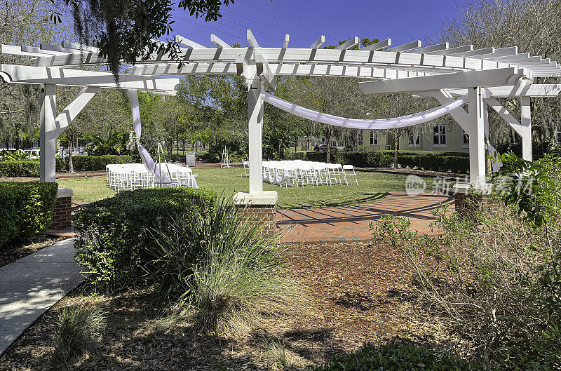 这个位于佛罗里达州基西米的湖滨公园有一个户外婚礼亭，配有便携式座椅，凉棚，砖砌人行道，周围环绕着树木和景观